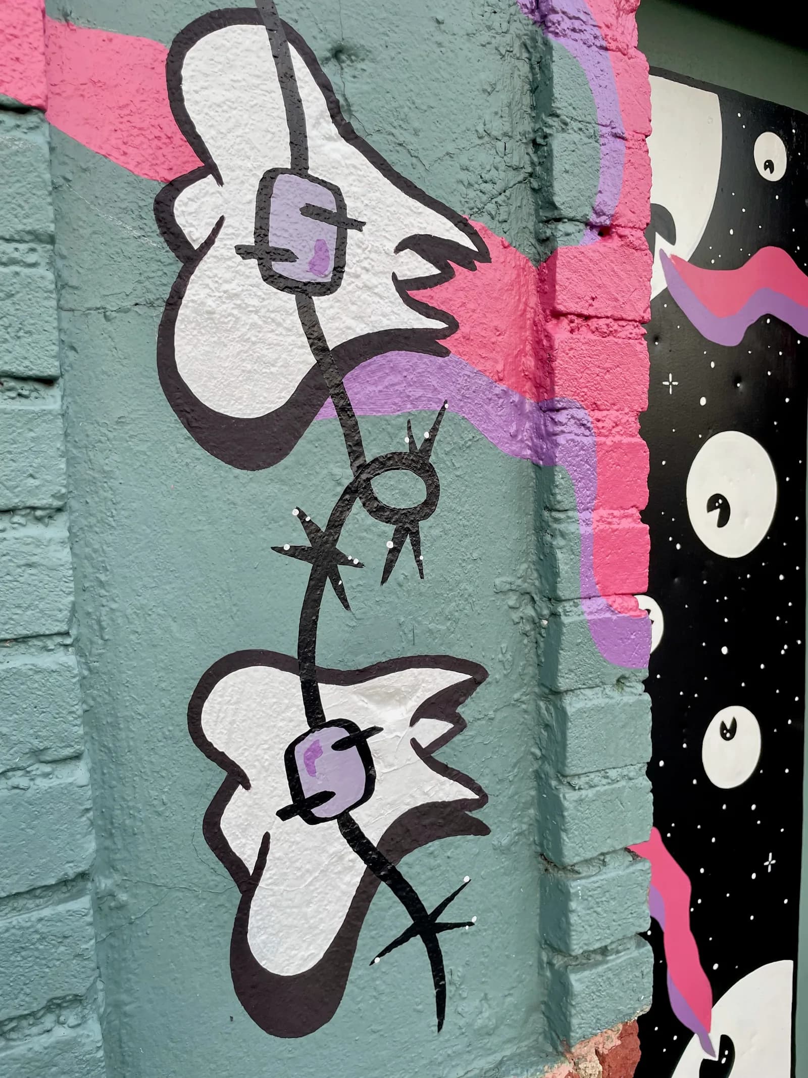Detail of the “Searchin'” mural — braces-clad teeth on barbed wire wrapping the corner pillar